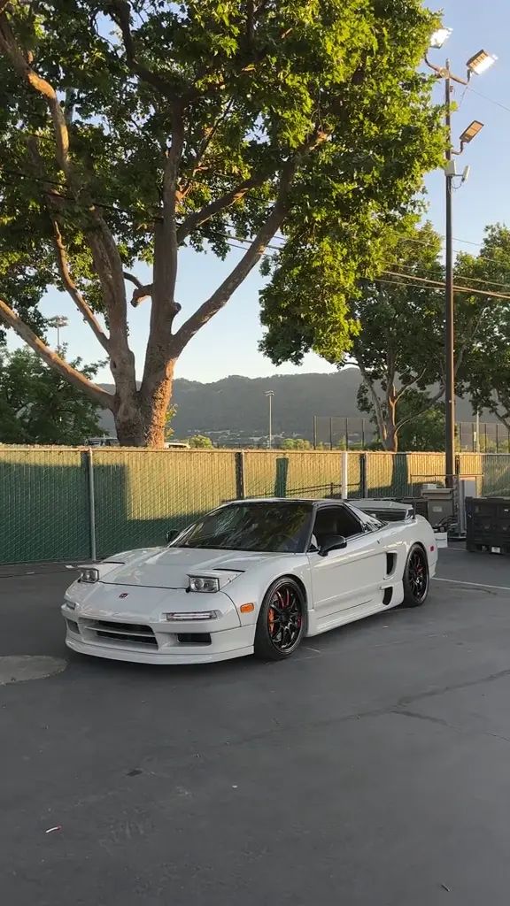 Original source poster from Magic Hour AI Video Editor: a white sports car parked beside trees and a fence.